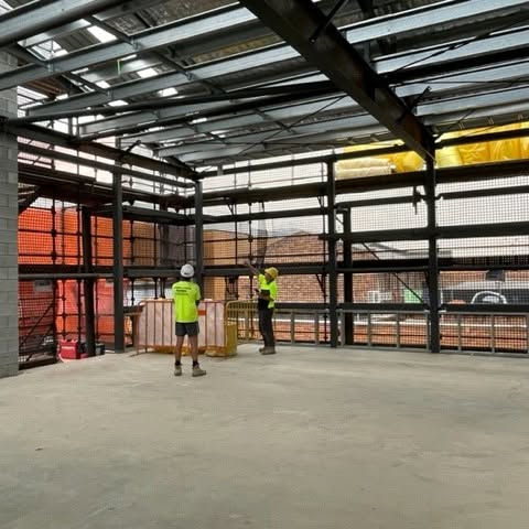 TCP crew on a commercial steel-frame fit-out, working under a structural steel ceiling grid in Toowoomba